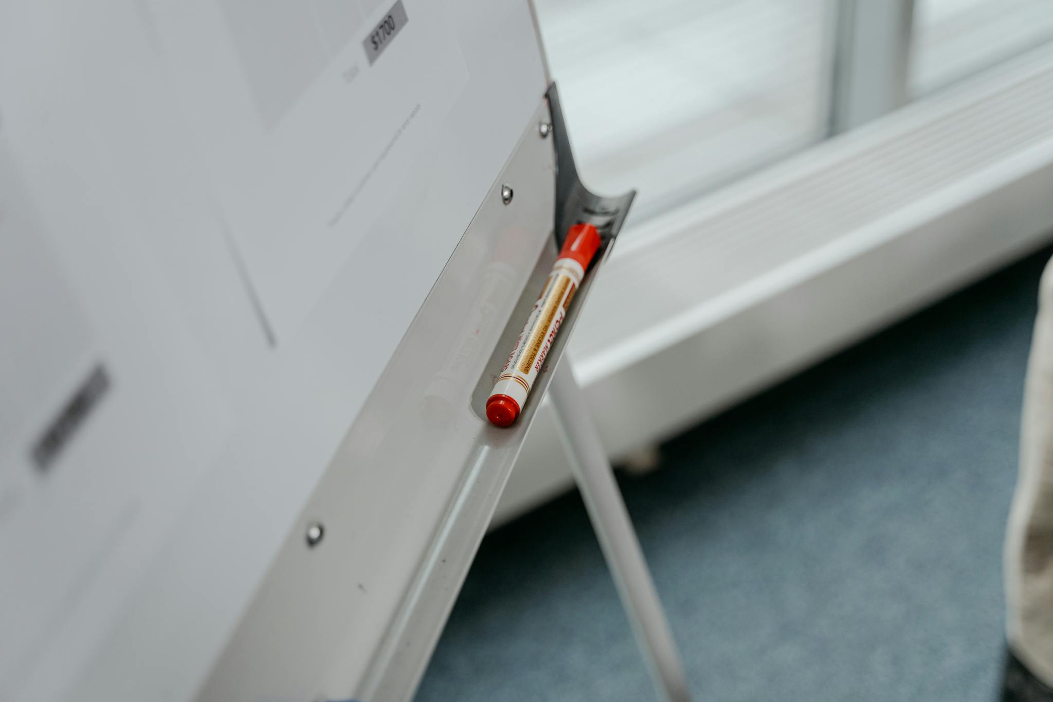 A whiteboard with a red marker resting on the tray, captured in a modern office setting.