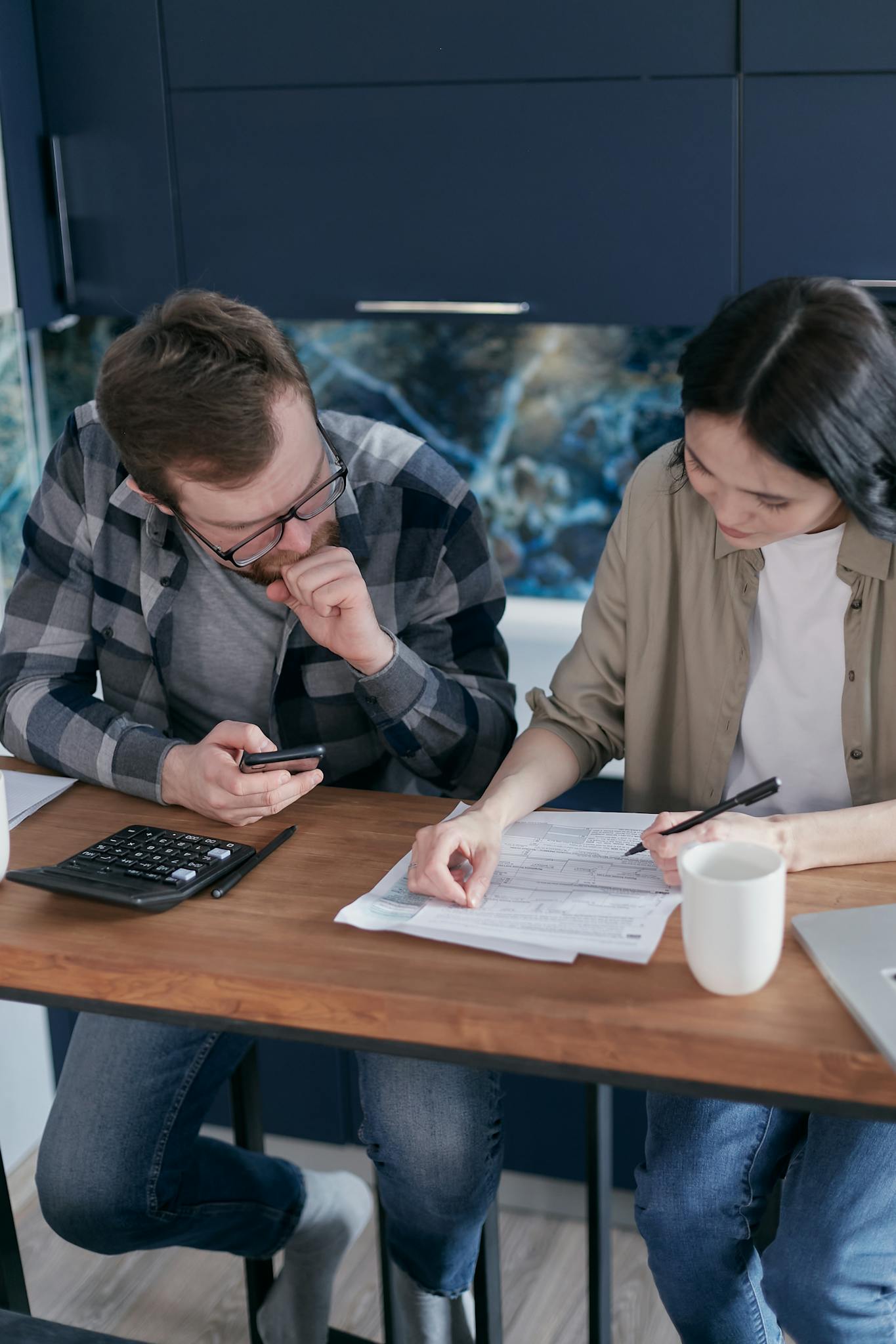 Two adults reviewing financial papers together indoors, focused on teamwork.